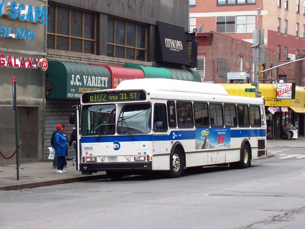All-Door Boarding Is Speeding Up Crowded City Bus Routes Passengers boarding a city bus on a busy street with buildings and traffic in the background.