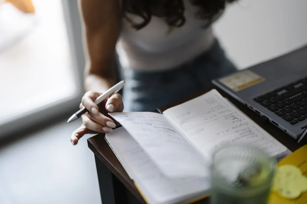 Person writing in a notebook while sitting at a desk