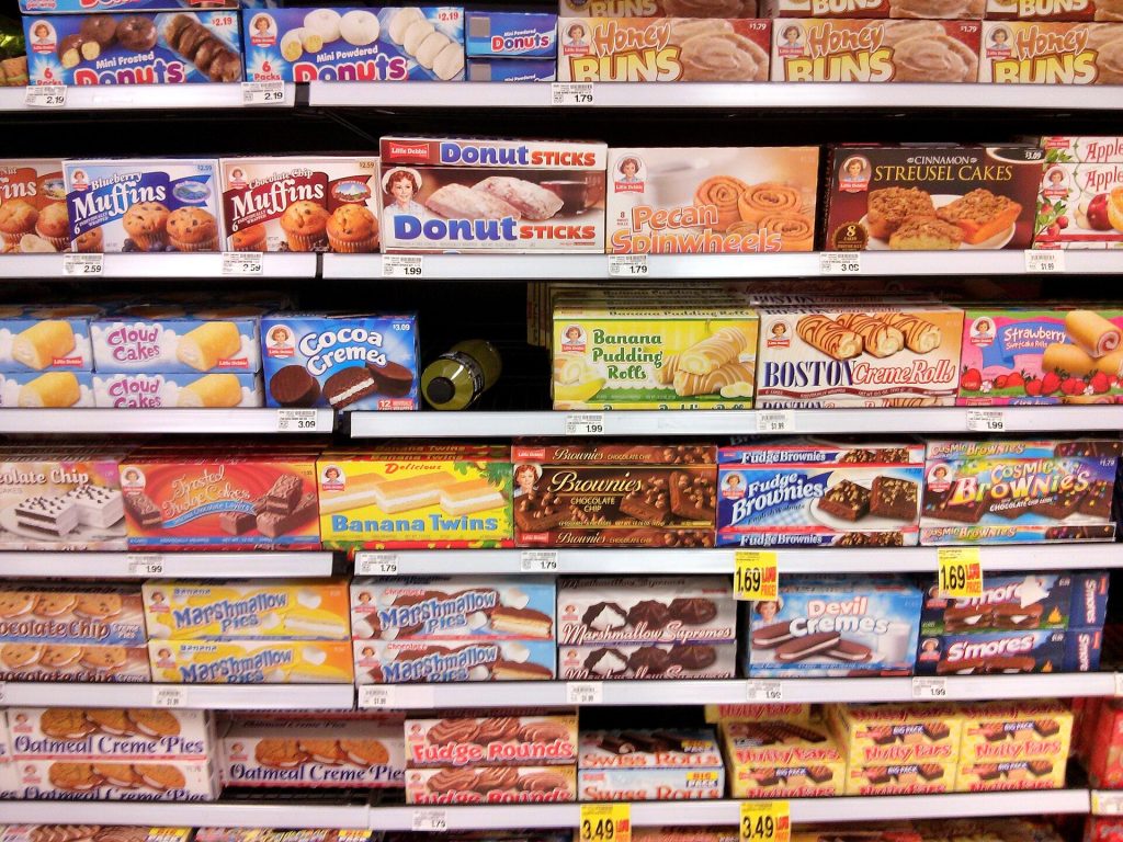 Ultra-Processed Food Definition Debate Shaped by Industry Links, Researchers Say Person reading food labels on packaged products in a supermarket